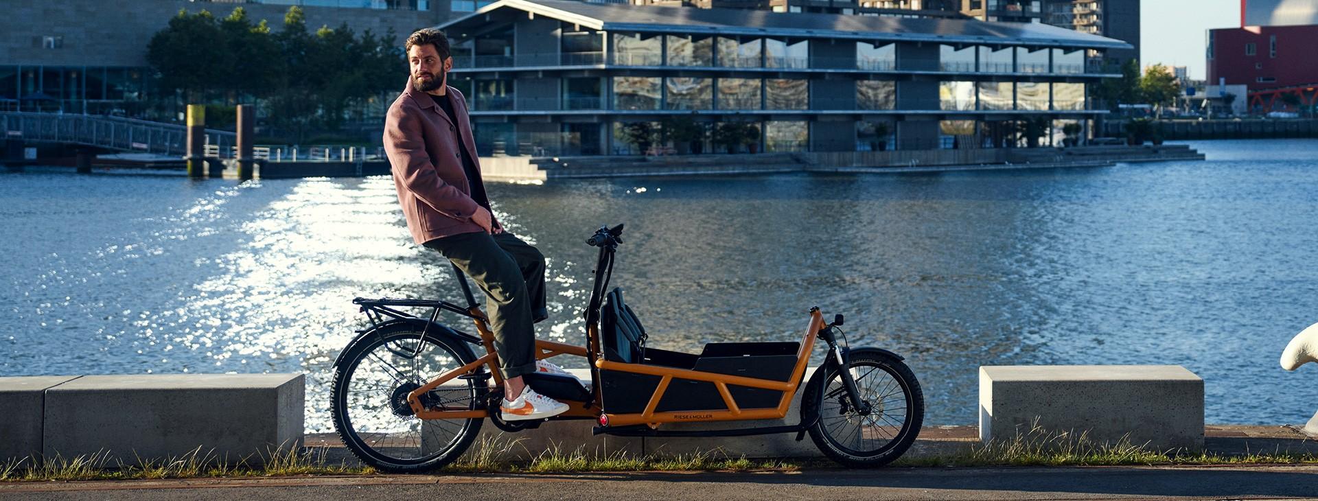 Ein Mann sitzt auf Riese & Müller Load4 75 direkt am Wasser