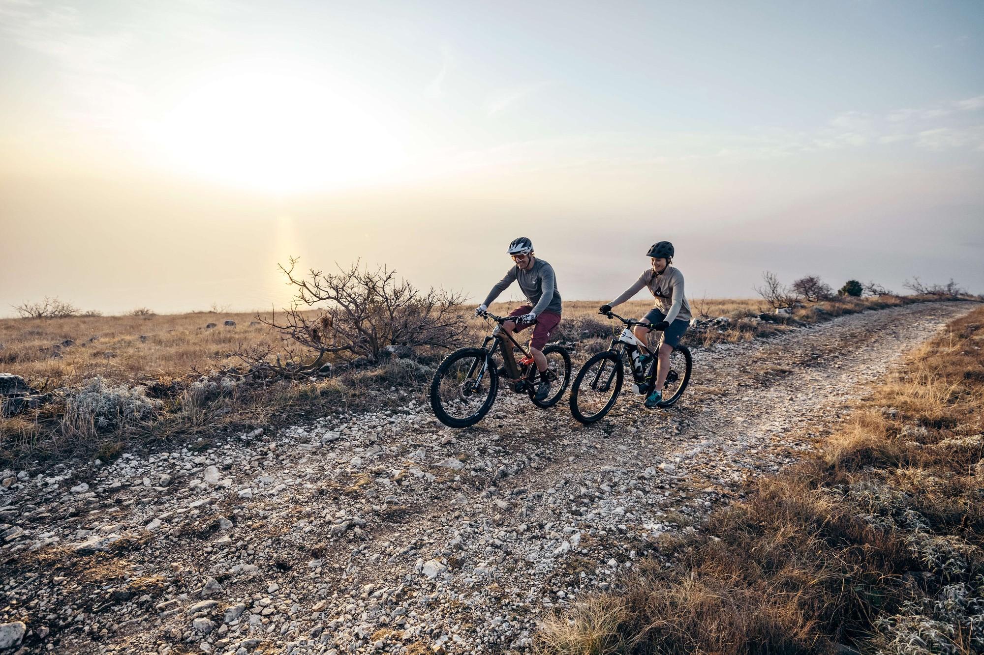 Zwei Personen fahren mit Husqvarna Mountain e-Bikes über unebene Wege