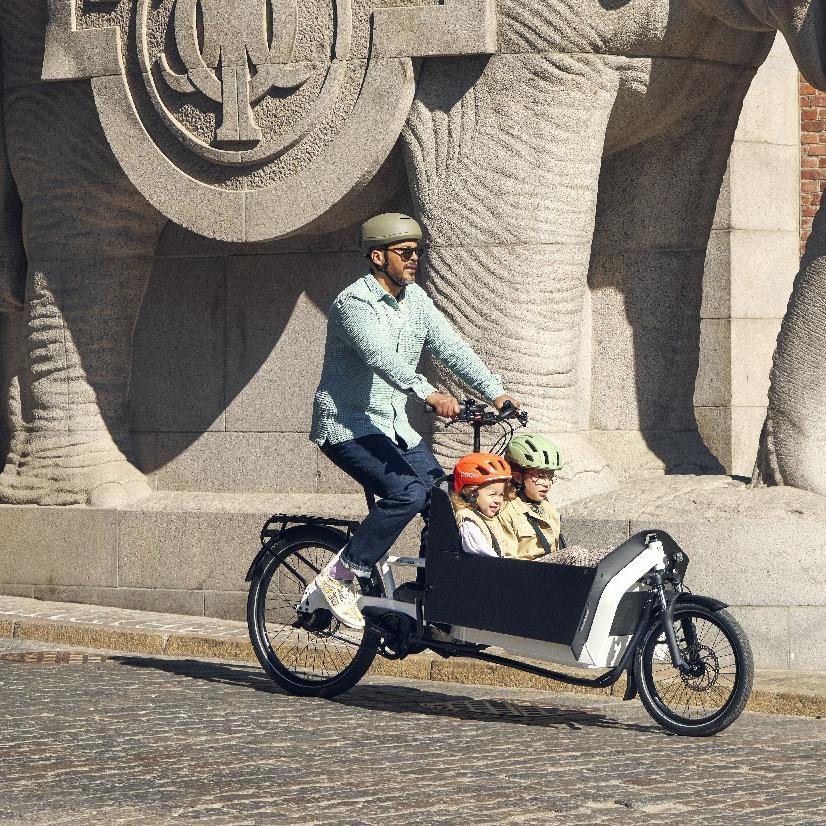 Ein Mann fährt mit Kindern in der Transportbox im Riese & Müller Transporter2