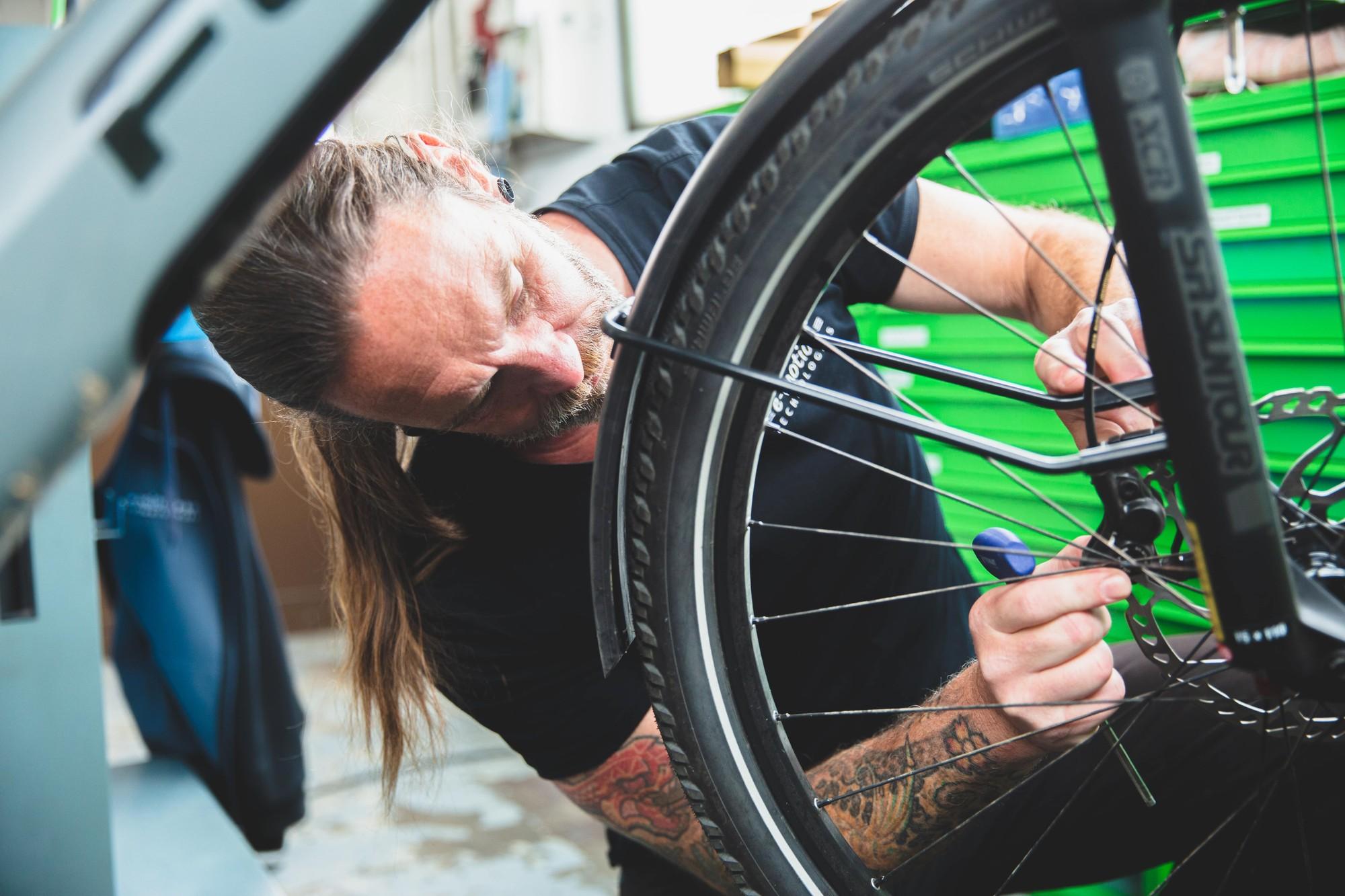 Das Bild zeigt einen Mechaniker, der sich auf die sorgfältige Wartung eines E-Bikes konzentriert.