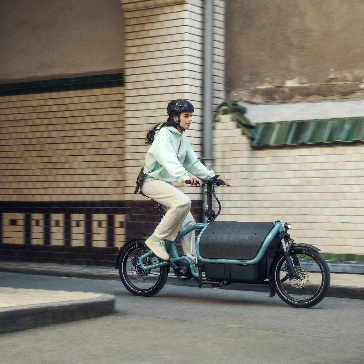 Eine Frau fährt auf dem Riese & Müller Carrie durch einen Tunnel in urbaner Umgebung