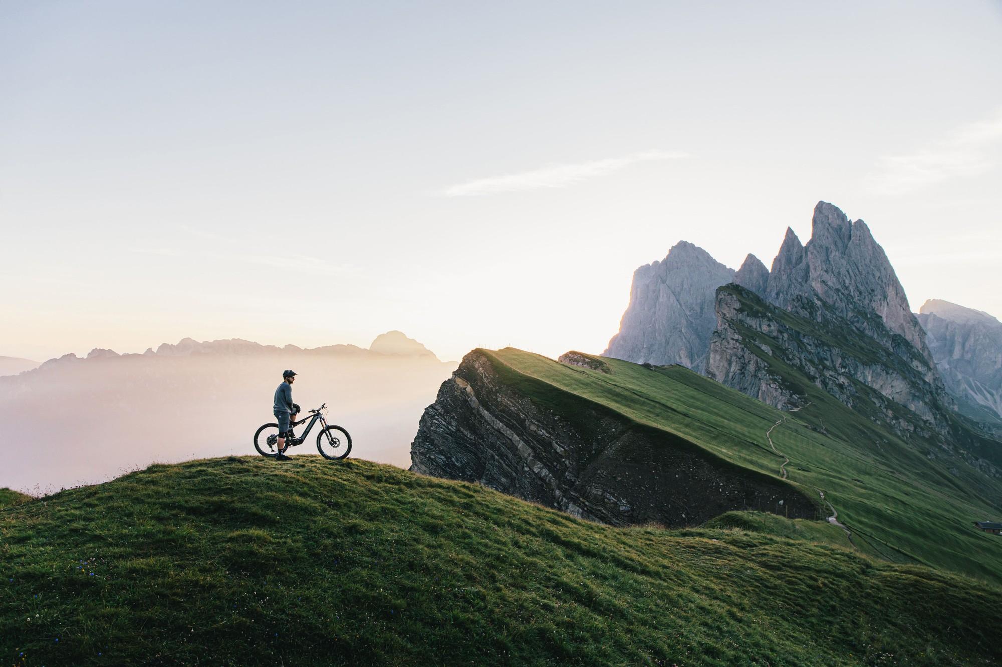 Radfahrer steht mit dem M1 FullGravel FG SX e-Mountainbike auf einem Bergrücken in den Dolomiten.