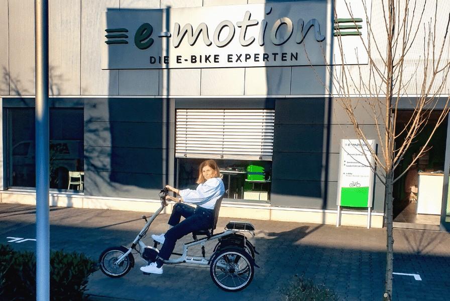 Eine Frau sitzt auf dem pfautec Scoobo und steht vor dem e-motion Shop