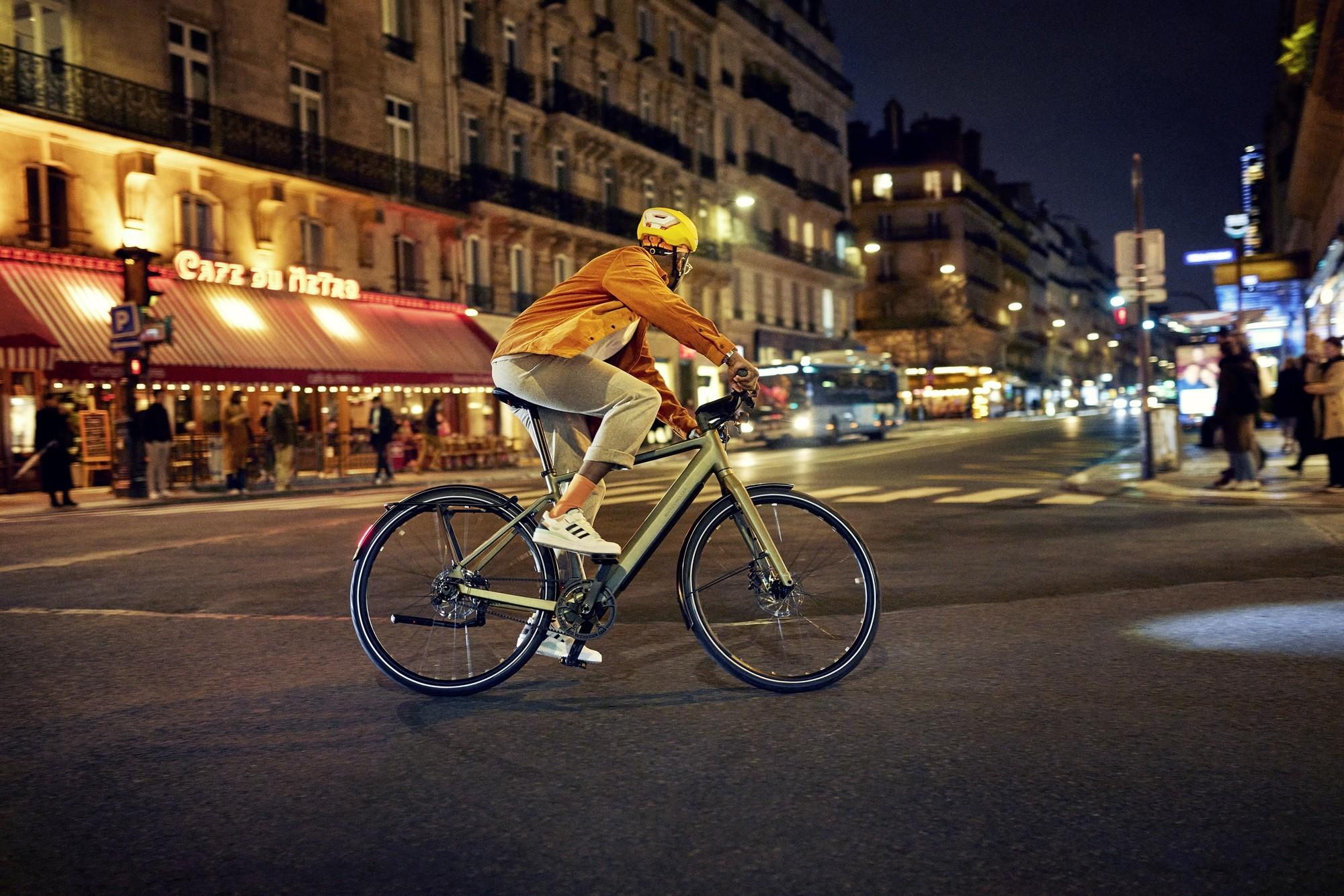 Das Bild zeigt ein Riese & Müller UBN Five E-Bike, das in einer urbanen Umgebung bei Nacht gefahren wird.