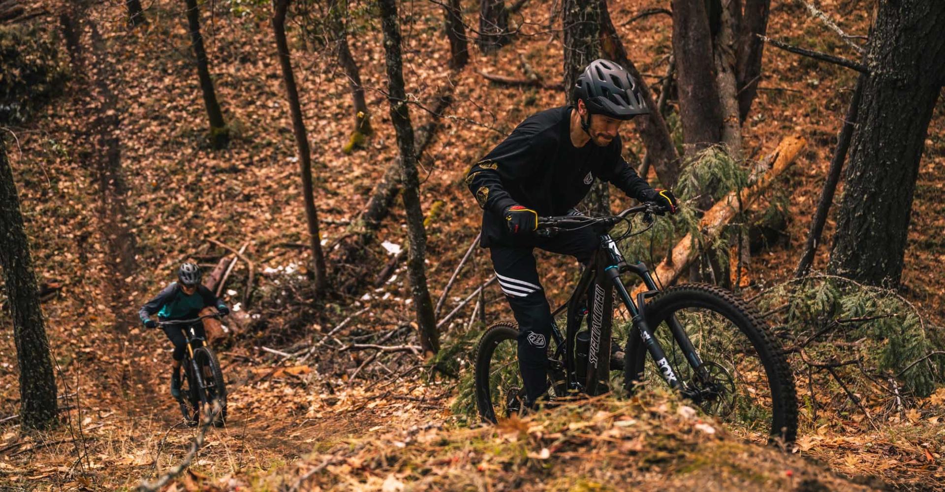 Zwei Biker fahren auf dem Specialized Turbo Levos e-Mountainbike im Herbst einen Hang hoch.