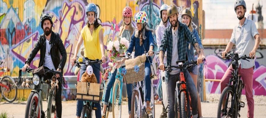 Gruppe von Menschen mit E-Bikes vor bunter Graffiti-Wand