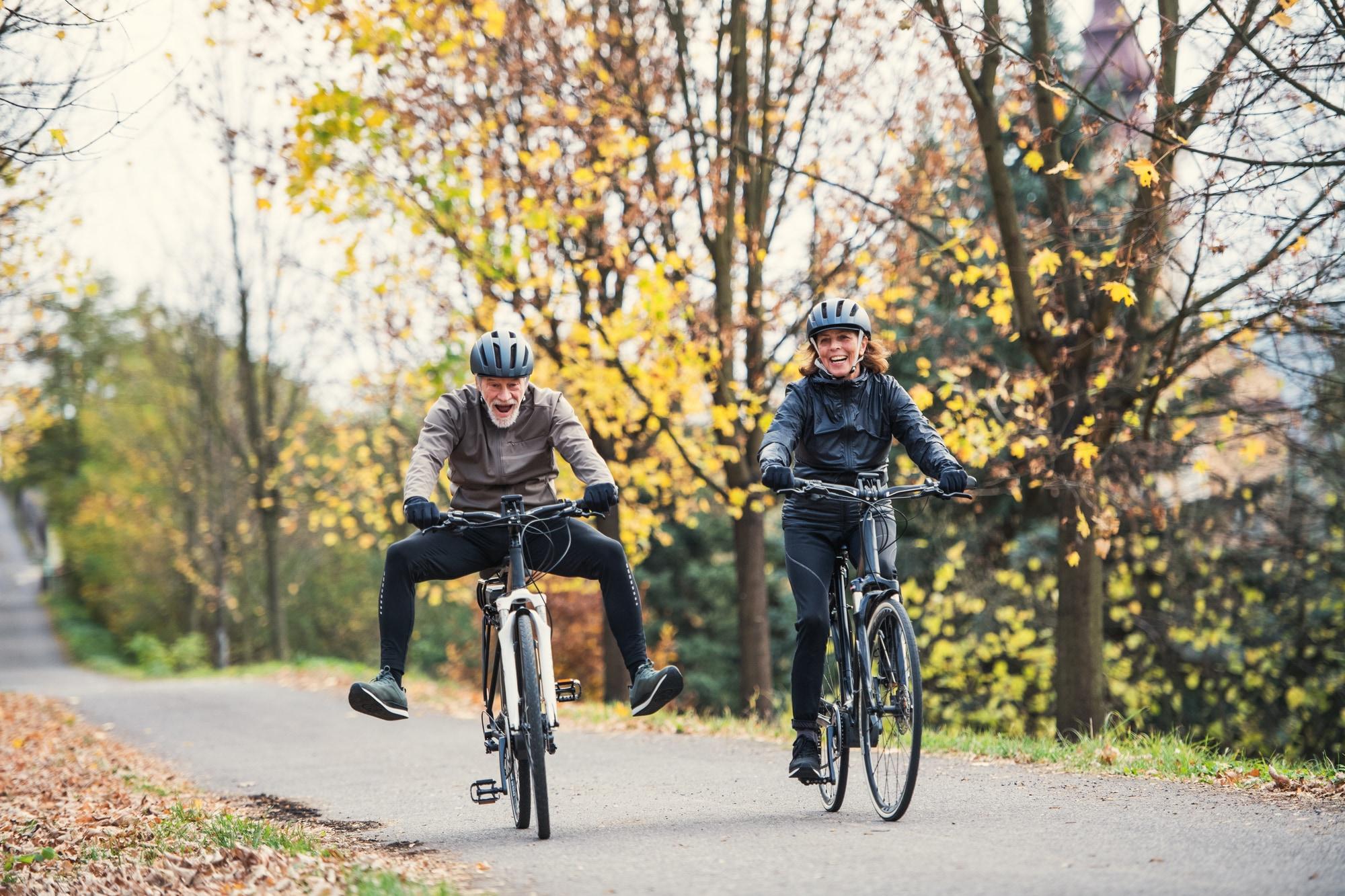 Zwei Senioren genießen die herbstliche Natur auf Fahrrädern. Perfekt für aktive Freizeitgestaltung und Erholung an
