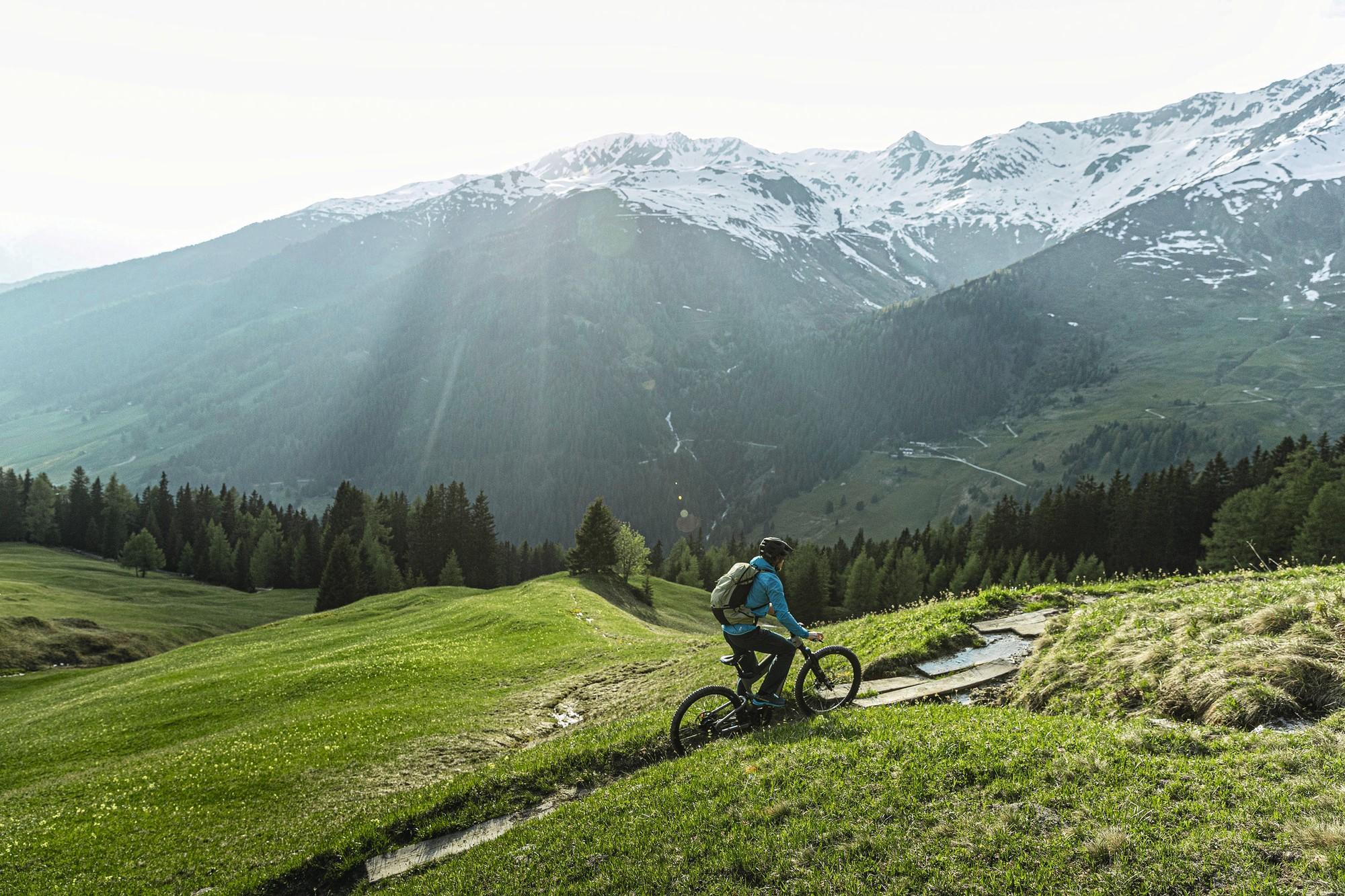 Das Bild zeigt einen Radfahrer, der auf einem Superdelite Mountain E-Bike ein malerisches alpines Gelände erkundet.