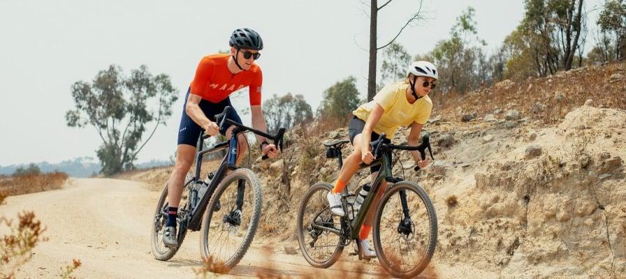 Zwei Personen fahren Cannondale Topstone Carbon Lefty Fahrräder auf Schotterweg