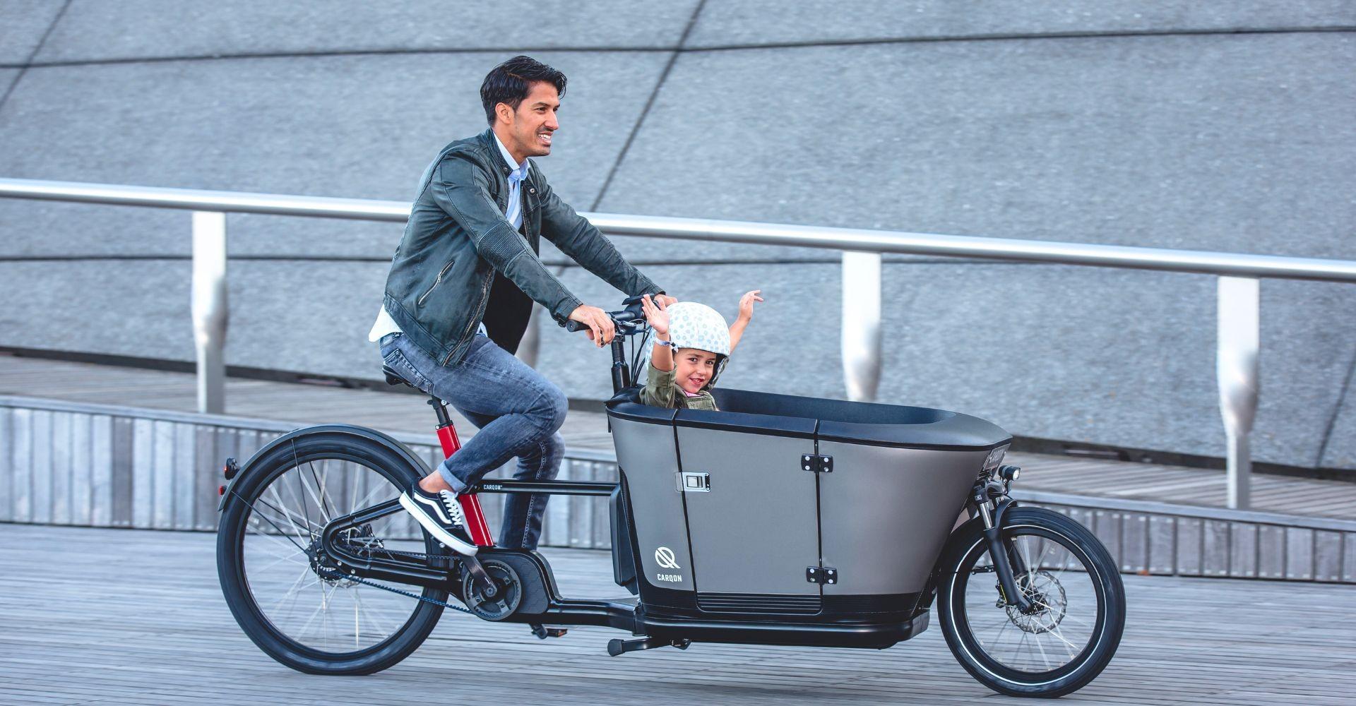 Ein Mann fährt auf dem Carqon Classic mit Kind in der Transportbox