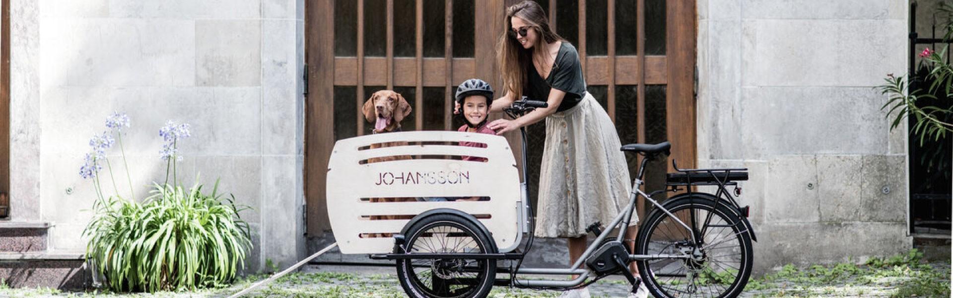 Frau steht neben dem Johansson Lastenrad, in der Transportbox Kind und Hund
