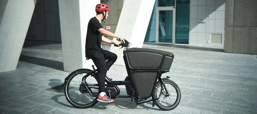 Mann auf Lastenfahrrad vor modernem Gebäude