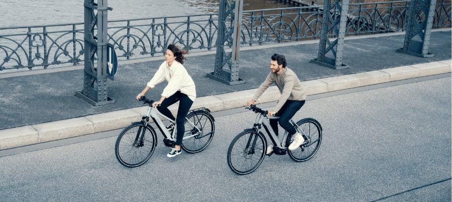 Zwei Personen fahren Riese & Müller E-Bikes auf einer Brücke