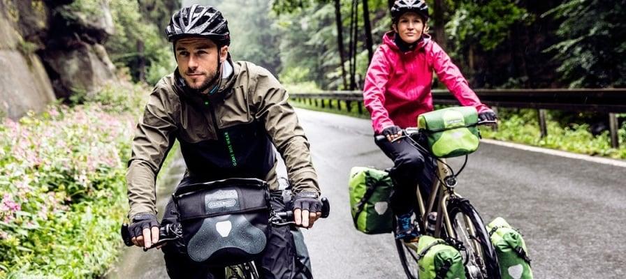 Zwei Radfahrer mit Ortlieb-Fahrradtaschen auf nasser Waldstraße