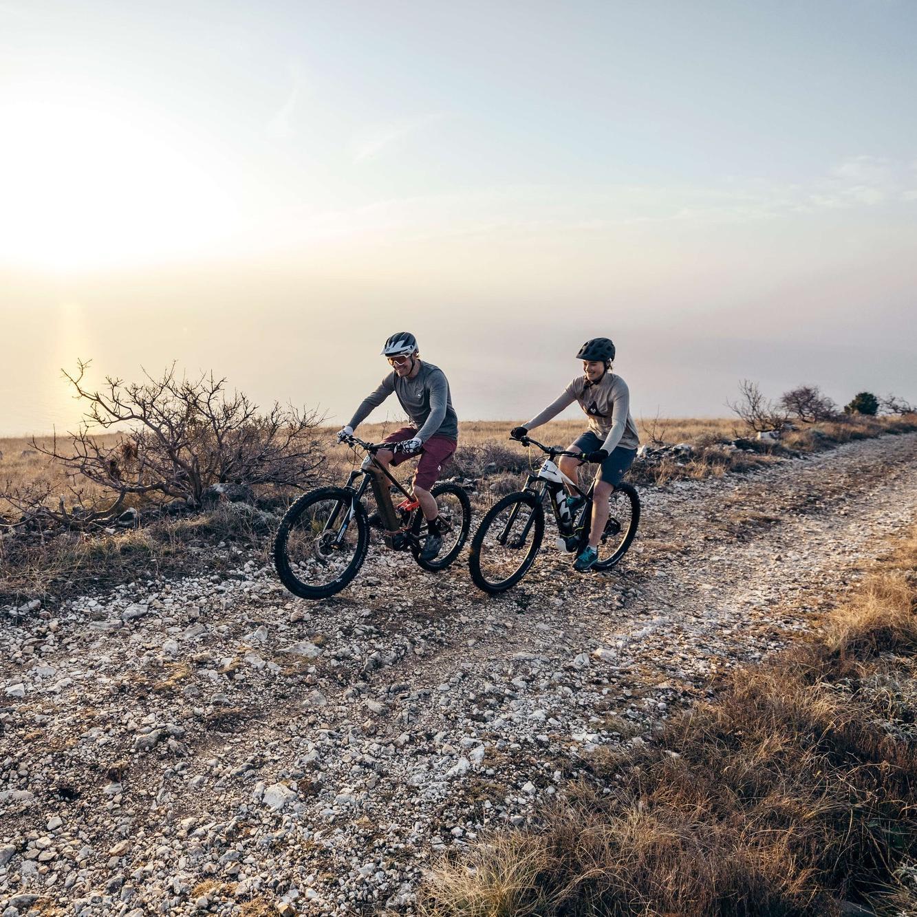 Zwei Personen fahren mit Husqvarna Mountain e-Bikes über unebene Wege