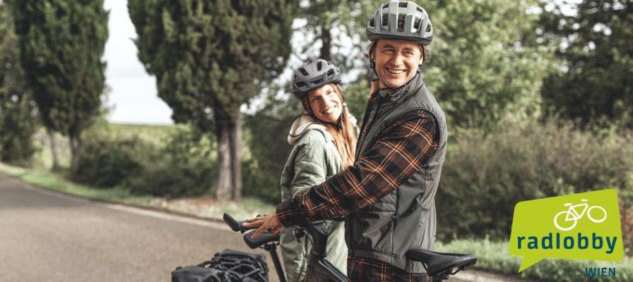 Zwei Personen mit Fahrrädern auf einer Landstraße, Radlobby Wien Logo