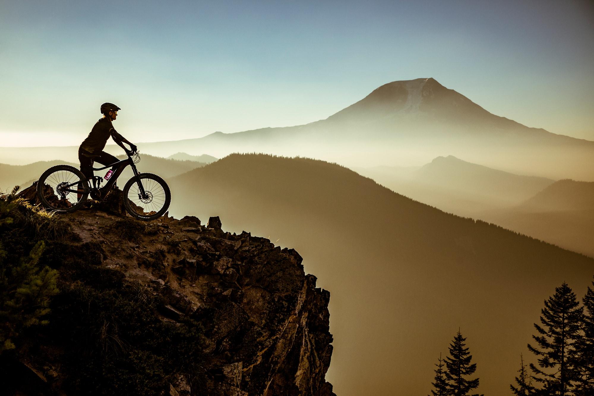 Ein Radfahrer auf einem E-Bike genießt die atemberaubende Aussicht von einem Berggipfel. Perfekt für Abenteuer und