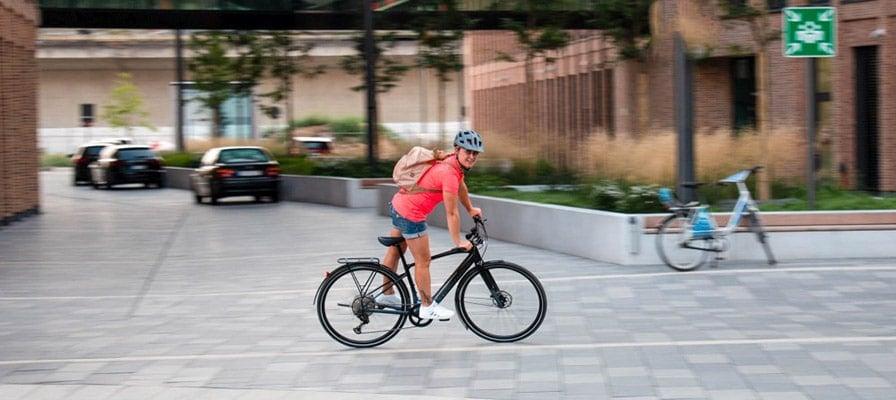 Person auf E-Bike in urbaner Umgebung mit Helm und Rucksack