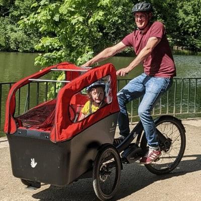 Triobike Boxter Lastenrad mit Kind am Seeufer