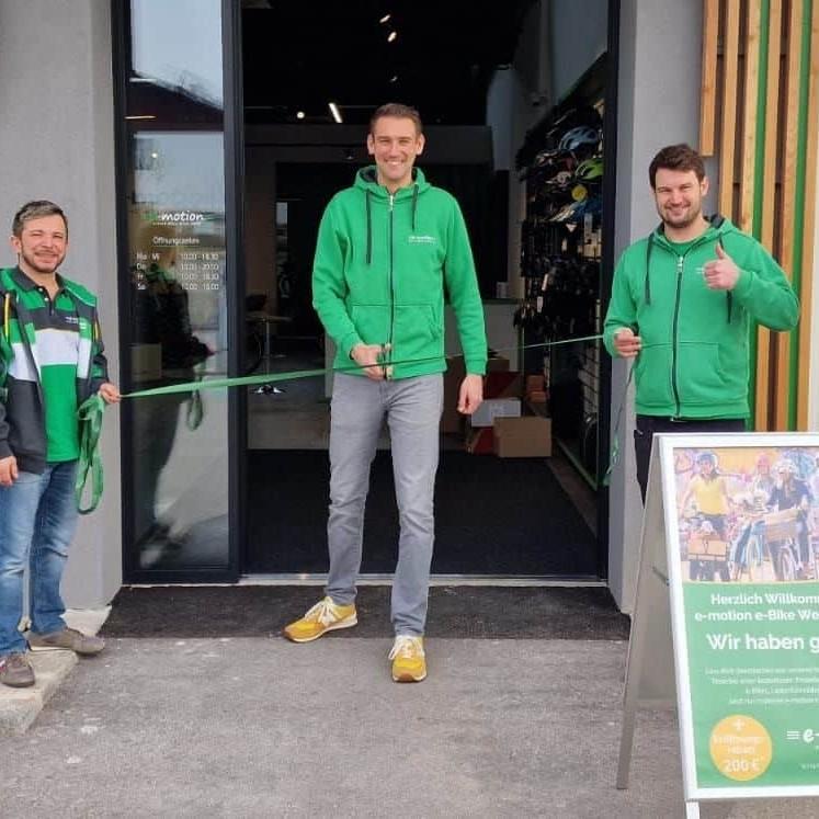 Eröffnung eines E-Bike-Shops mit vier Personen und Werbeschild