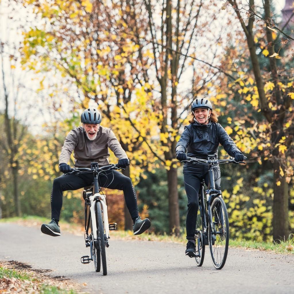 Zwei Senioren genießen die herbstliche Natur auf Fahrrädern. Perfekt für aktive Freizeitgestaltung und Erholung an