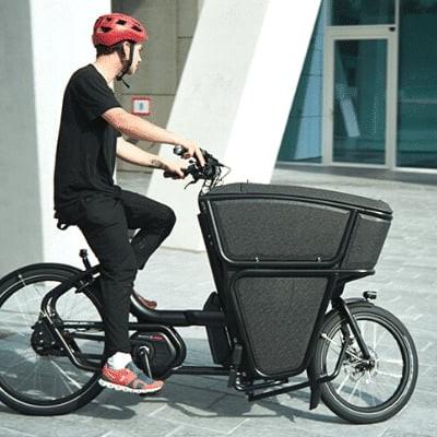 Mann auf Lastenfahrrad vor modernem Gebäude