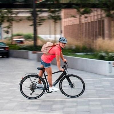 Person auf E-Bike in urbaner Umgebung mit Helm und Rucksack