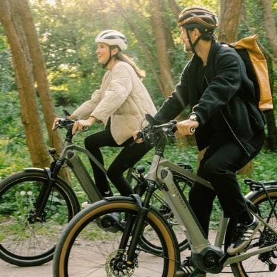 Zwei Radfahrer auf E-Bikes im Wald bei sonnigem Wetter