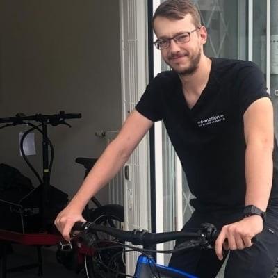 Mann mit E-Bike vor einem Geschäftseingang