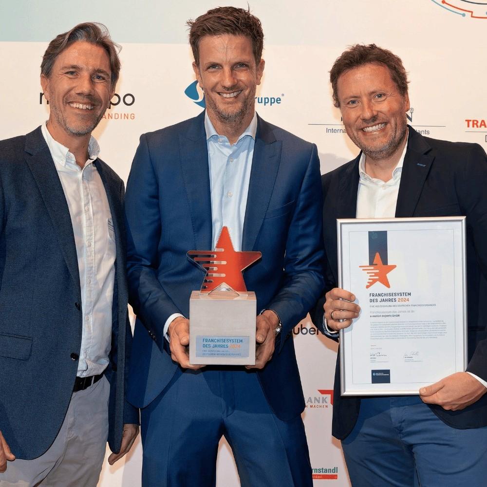 Gruppe von Personen mit Pokal und Blumen bei Outdoor-Event