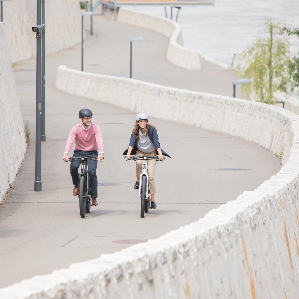 Zwei Personen fahren auf Stromer ST3 E-Bikes eine kurvenreiche Straße entlang. Ideal für moderne Mobilität und stil