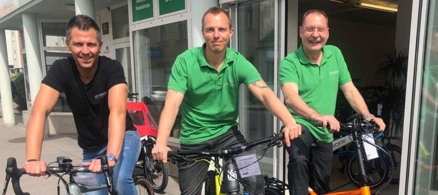 Drei Männer auf Fahrrädern vor einem Geschäft in Wien