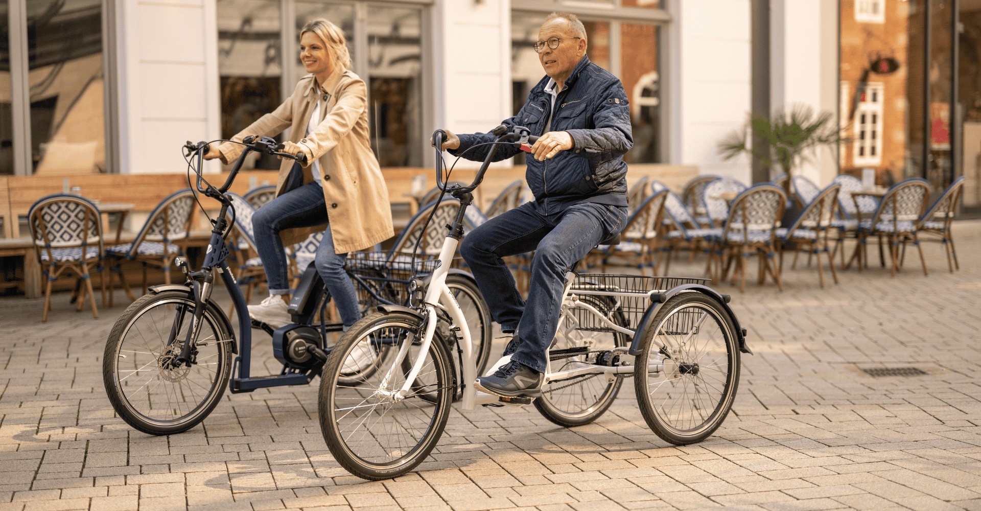 Eine junge Frau und ein Senior fahren mit einem pfautec Dreirad