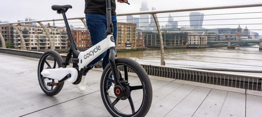 Gocycle E-Bike auf Brücke mit Stadt im Hintergrund