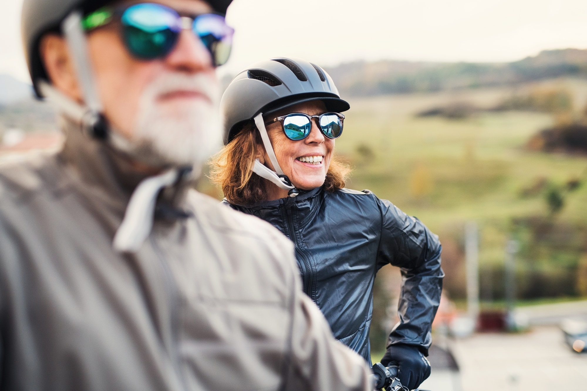 Zwei aktive Senioren in Outdoor-Bekleidung und Fahrradhelmen genießen die frische Luft. Ideal für Outdoor-Aktivität