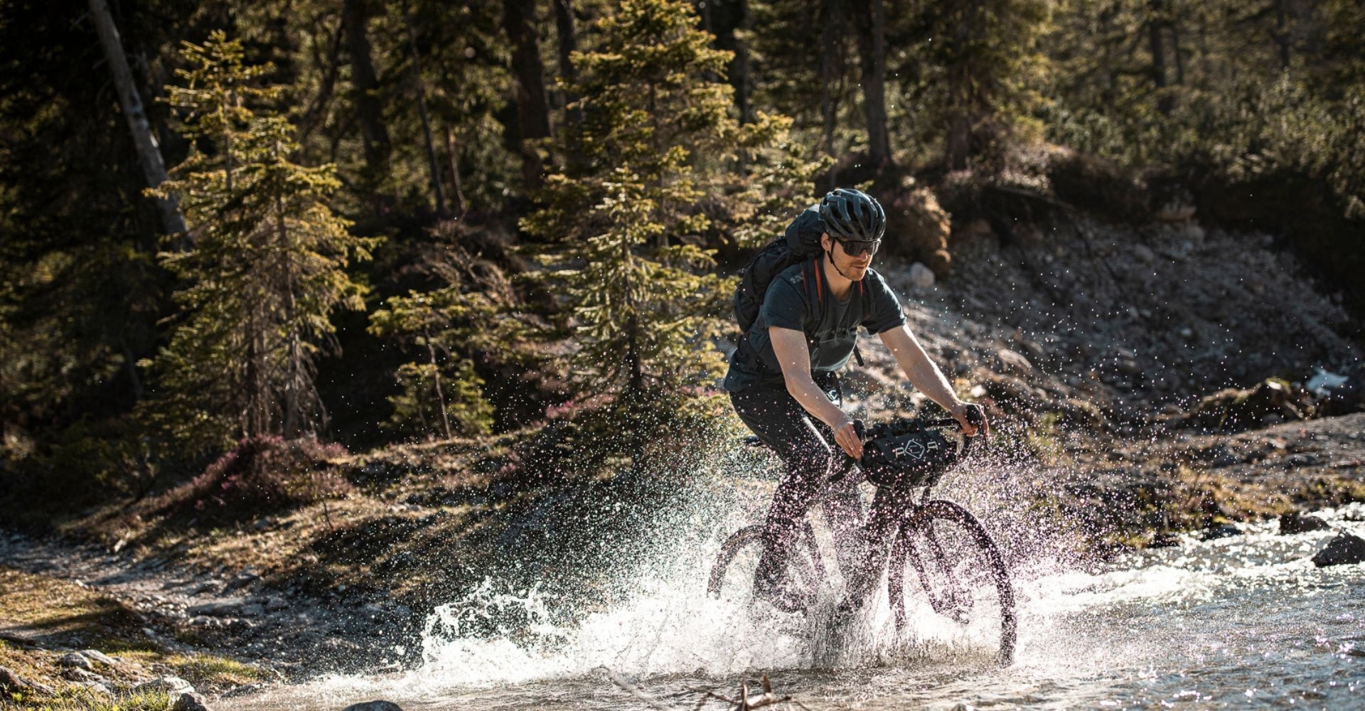 Mann fährt mit Gravel e-Bike durch das Wasser