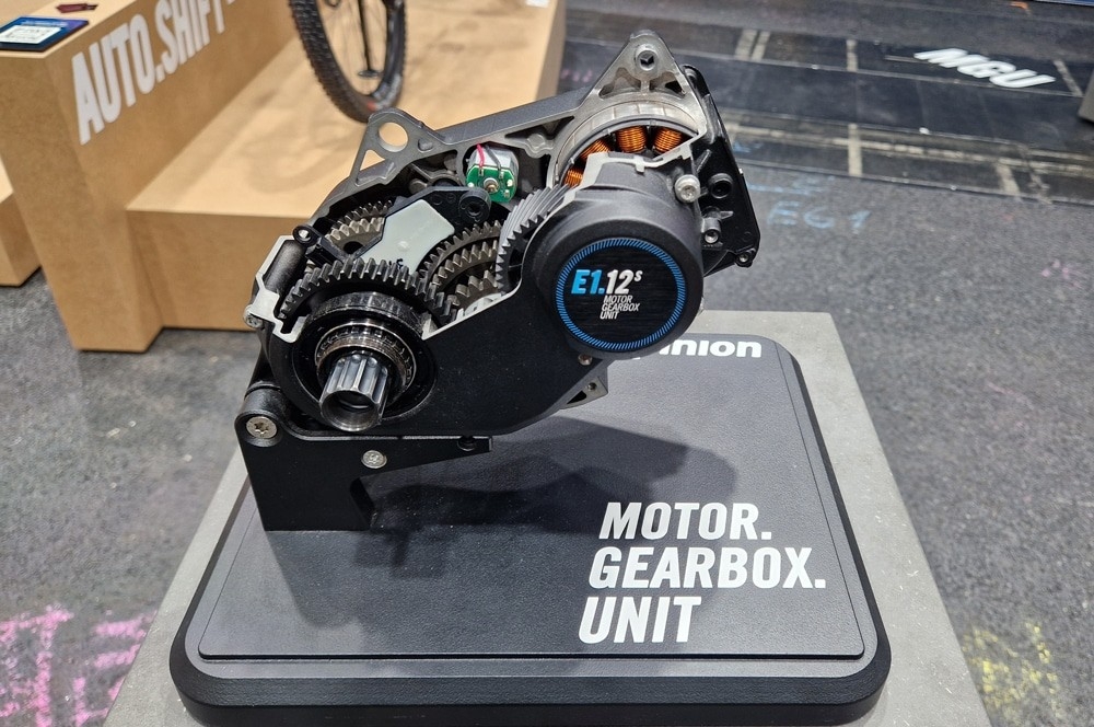 Pinion MGU Motor mit integriertem Getriebe, kompakt auf Ständer präsentiert, zeigt Zahnräder und moderne Technik.