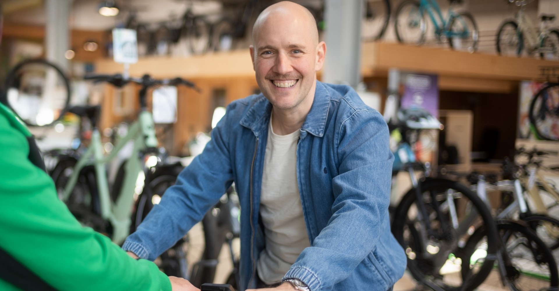 e-Bike Beratung. Mitarbeiter und Kunde lächeln zufrieden in die Kamera