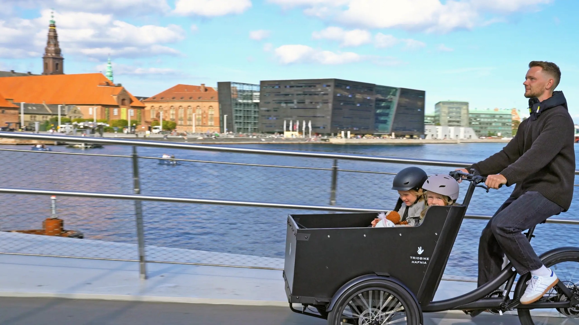 Das Bild zeigt ein Triobike Hafnia, ein modernes E-Lastenrad, das ideal für urbane Umgebungen ist.