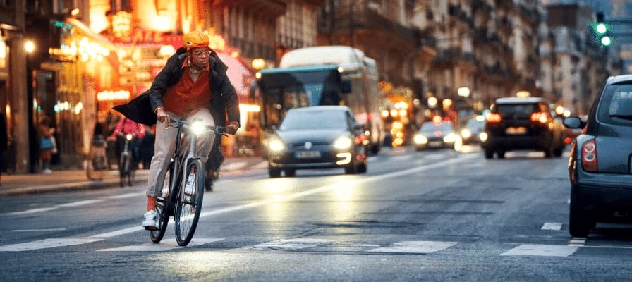 Mann auf Fahrrad bei Nacht in belebter Stadtstraße