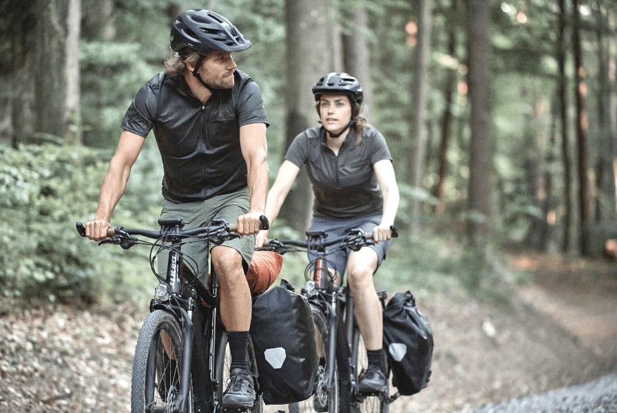 Zwei Radfahrer mit Gepäcktaschen im Wald