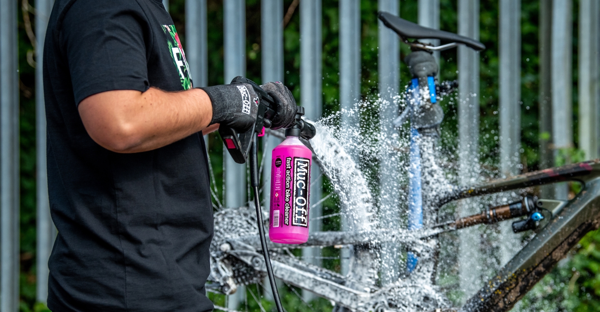 Ein Mann säubert ein e-Bike und sprüht es mit einem Reinigungsschaum von Muc-Off ein