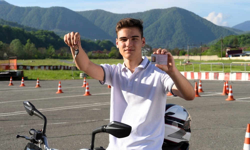 Das Bild zeigt einen jungen Mann, der stolz seinen Mofa-Führerschein in der Hand hält.