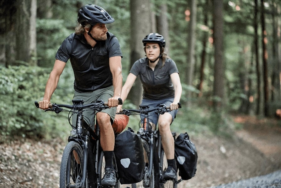 Zwei Radfahrer mit Gepäcktaschen im Wald auf Mountainbikes