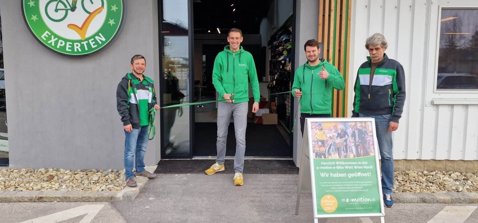 Eröffnung eines E-Bike-Shops mit vier Personen und Werbeschild