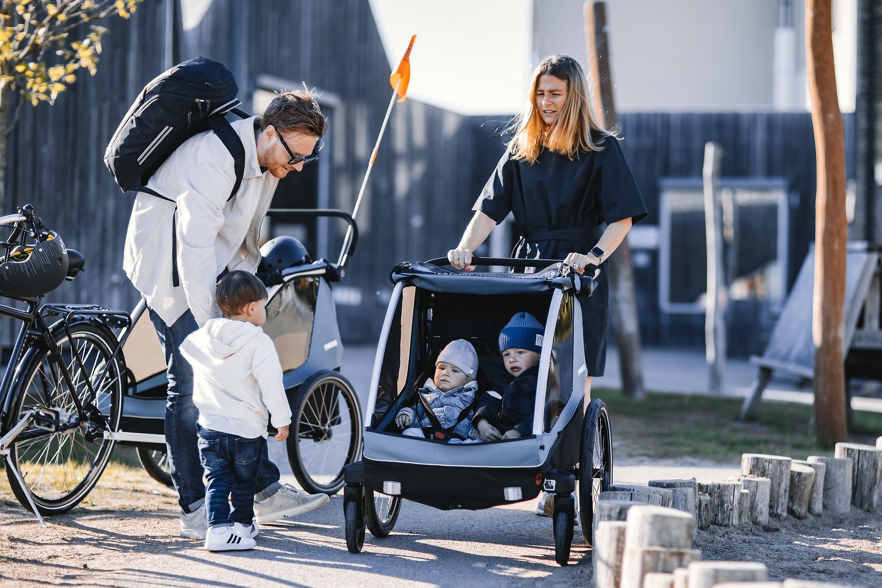 Das Bild zeigt eine Familie, die mit einem Thule Courir Kindersitz unterwegs ist.