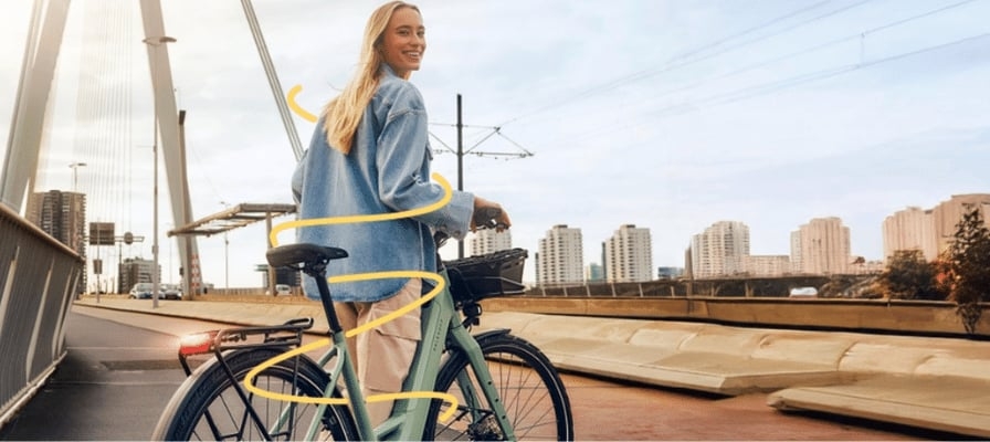 Frau mit E-Bike auf Brücke bei Sonnenuntergang in urbaner Umgebung