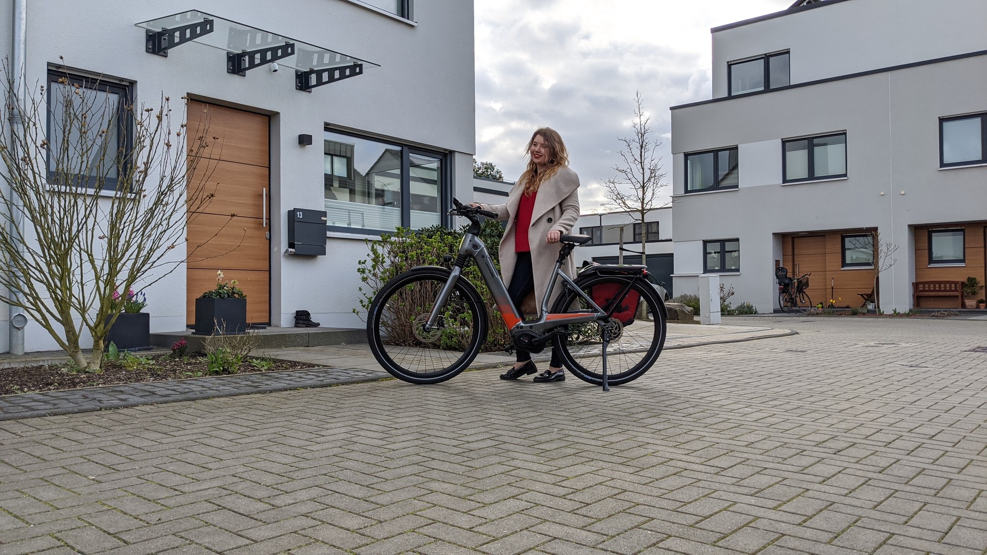 Britt steht vor einem Wohnhaus mit dem e-Bike Mavaro Neo von Cannondale