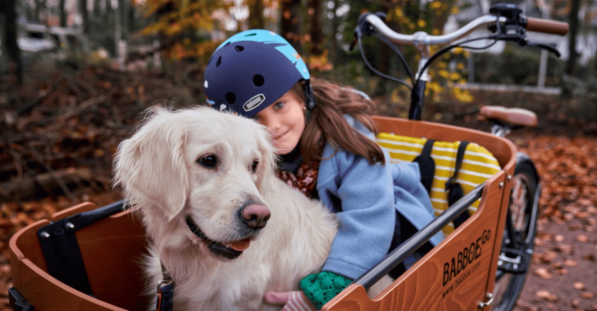 Ein Mädchen sitzt in der Transportbox des Babboe Go Lastenrades mit ihrem Hund