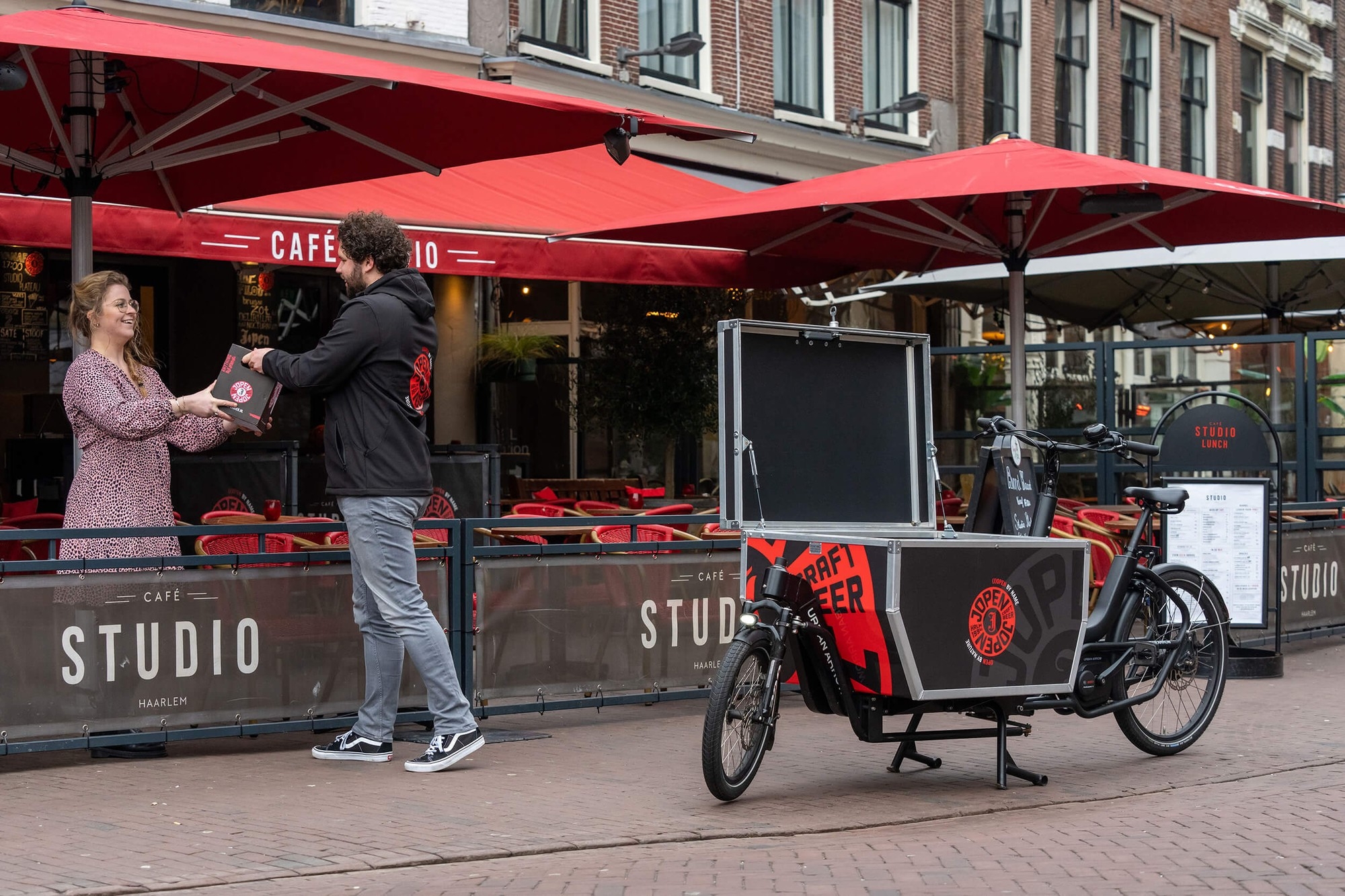 Das Bild zeigt ein Urban Arrow Cargo Tender, ein praktisches Lasten-E-Bike, das vor einem Café abgestellt ist.